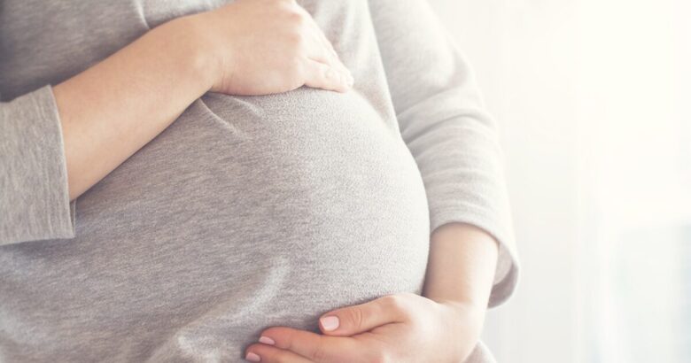 妊娠中の大きいお腹に手をあてる女性